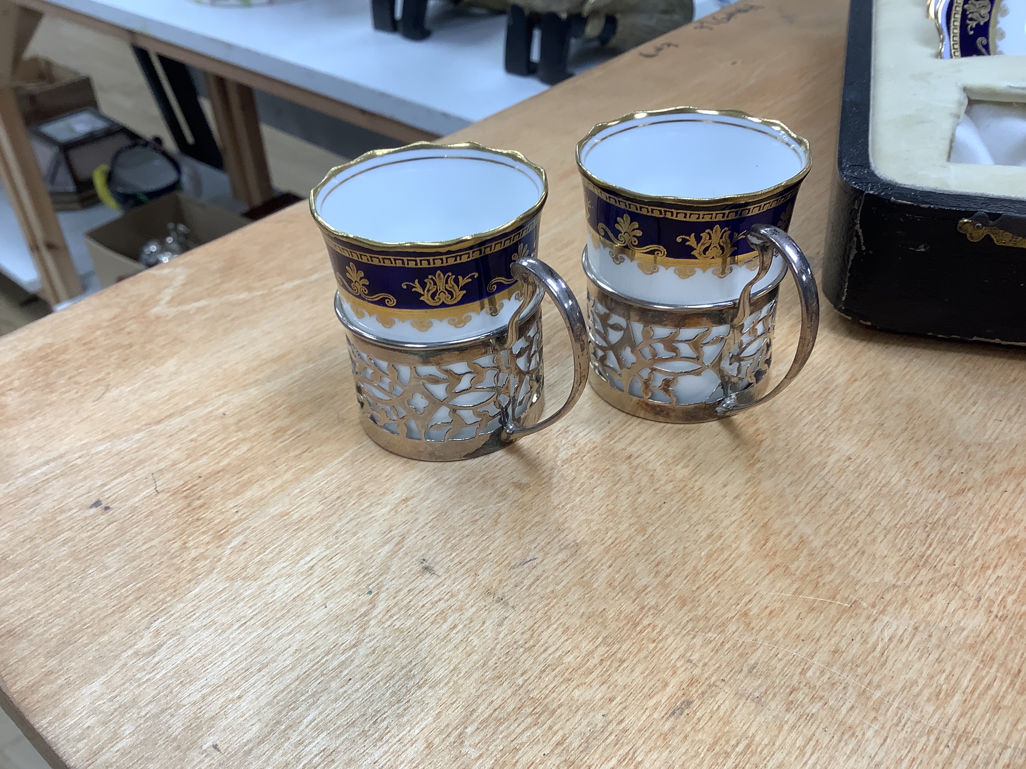 A cased George V set of six Aynsley coffee cans and saucers, the cans with pierced silver holders, C.S. Green & Co, Birmingham, 1924, can 57mm.